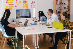 Equipo de una de las mejores agencias de diseño web reunidos en una mesa con pizarra y post-its